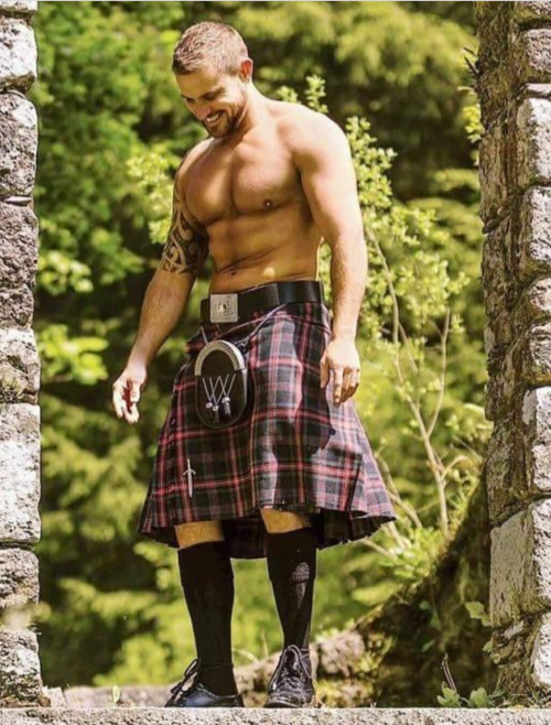 shirtless man walking in the woods in a kilt