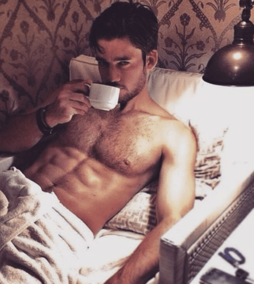 handsome guy drinking coffee in bed